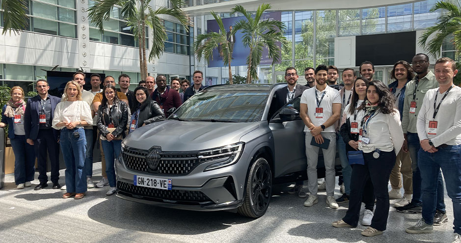 Groupe de personnes, principalement des adultes, posant ensemble devant un véhicule Renault Mégane de couleur grise