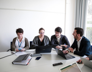 Groupe de personnes attablées discutent devant leurs ordinateurs portables