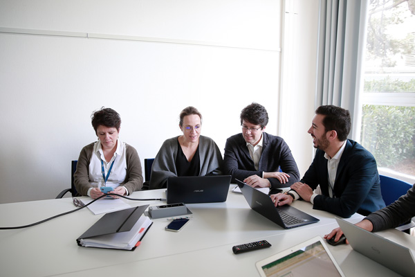 Groupe de personnes attablées discutent devant leurs ordinateurs portables