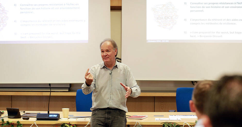 A professor delivering a presentation to a group of individuals in a professional setting