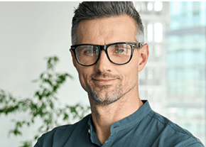 Souriant homme d'affaires mature et confiant regardant la caméra debout au bureau à la réunion d'équipe. Le directeur exécutif du chef d'entreprise masculin portant des lunettes posant pour des portraits d'entreprise est replié.